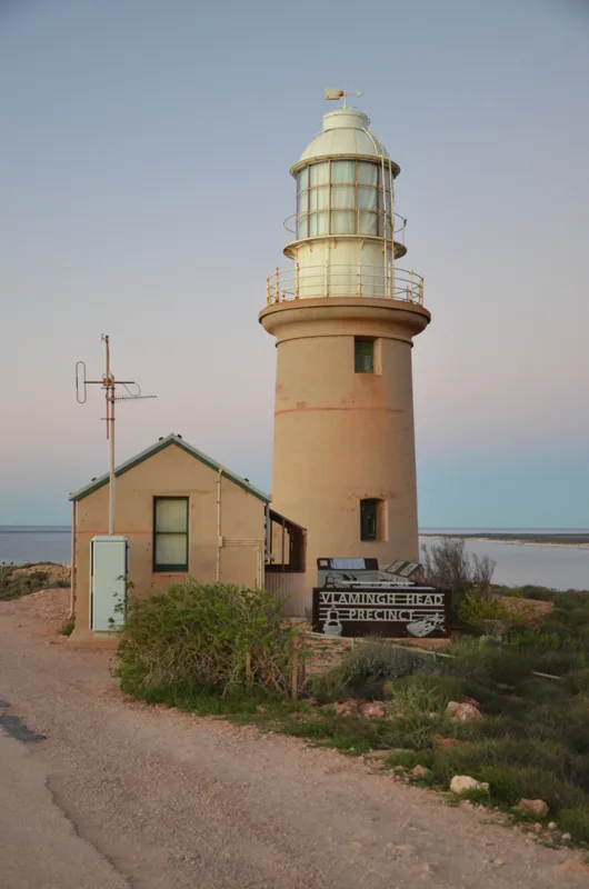 A lighthouse overlooking the coast beneath a pale sky.